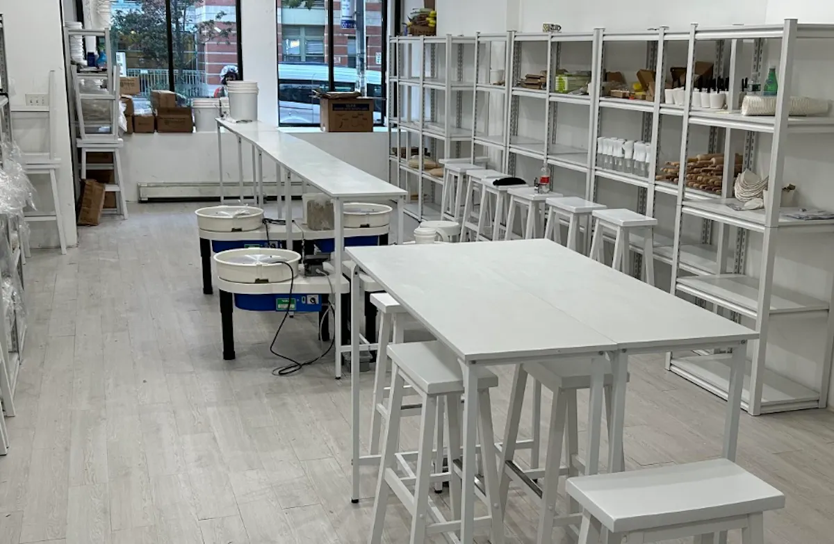 A bright pottery studio with worktables, stools and wheels ready for a class